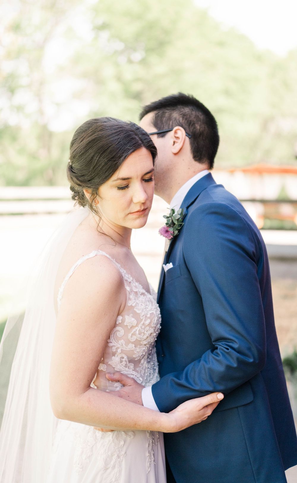 Intimate wedding portrait showing the bride's gown details and groom's navy suit.
