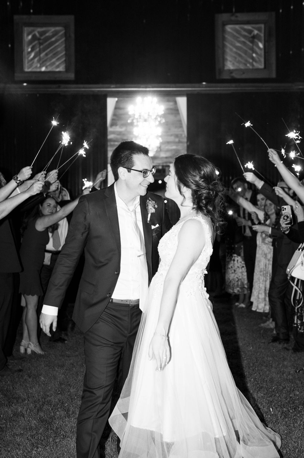 Wedding couple's sparkler exit with guests creating a magical nighttime tunnel.