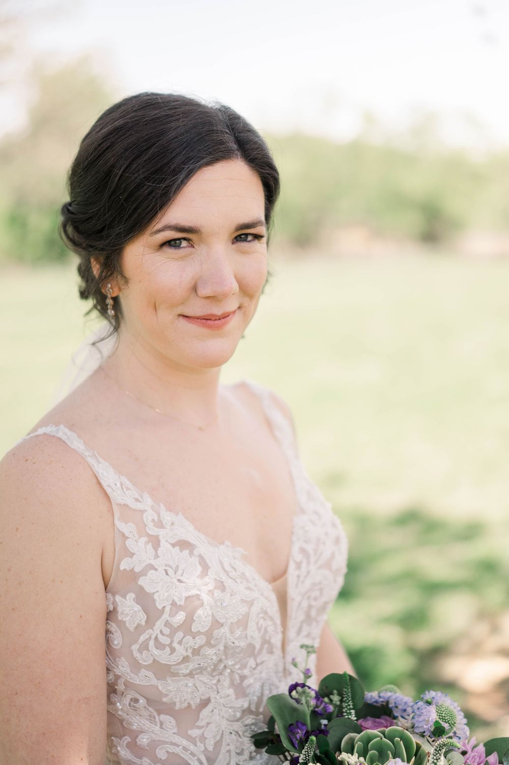 Beautiful bridal portrait outdoors with a bouquet featuring purple flowers.