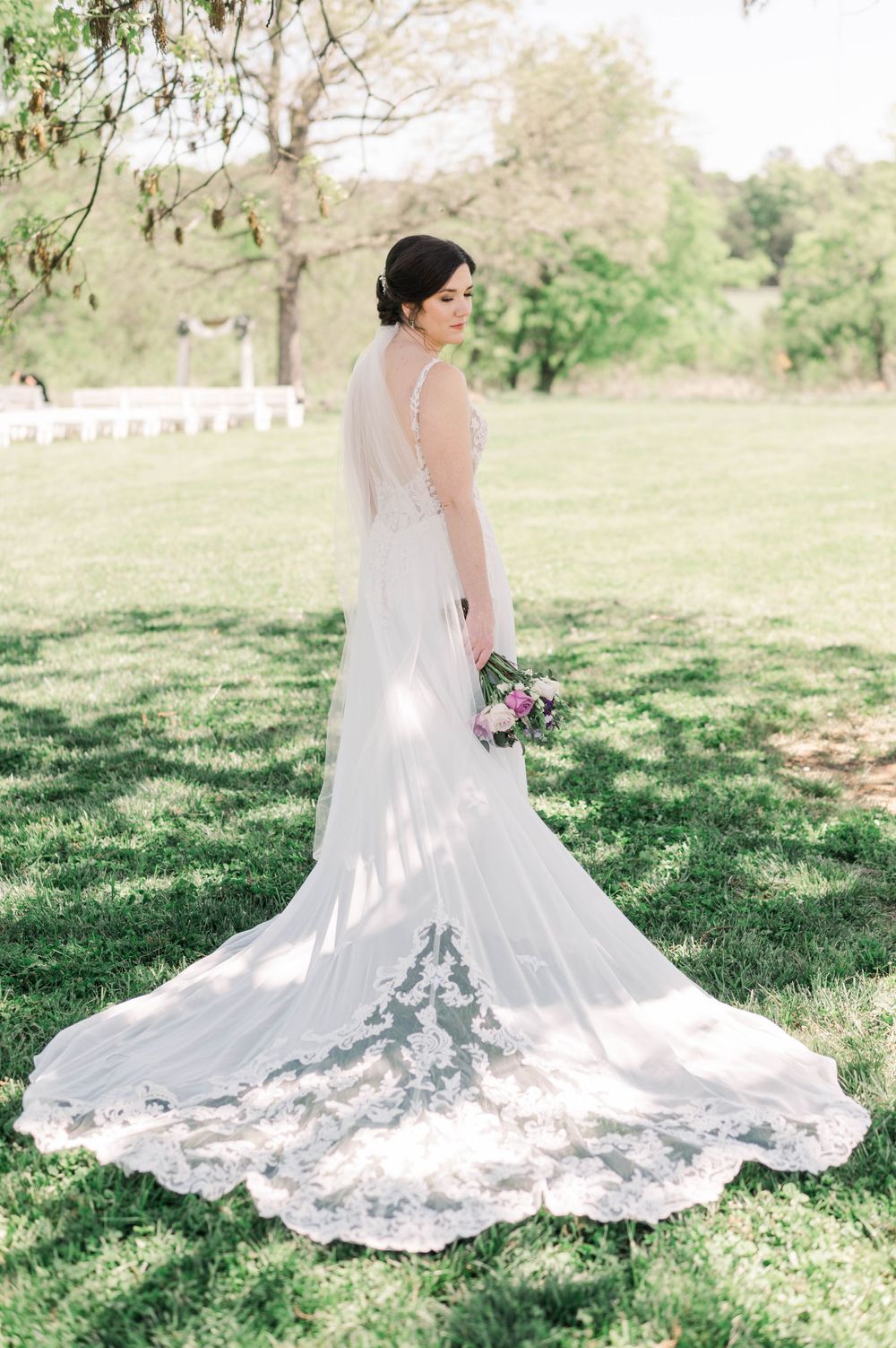 Full-length view of a wedding dress with stunning lace train on green grass. The 1932 Barn Venue, Charlotte, NC