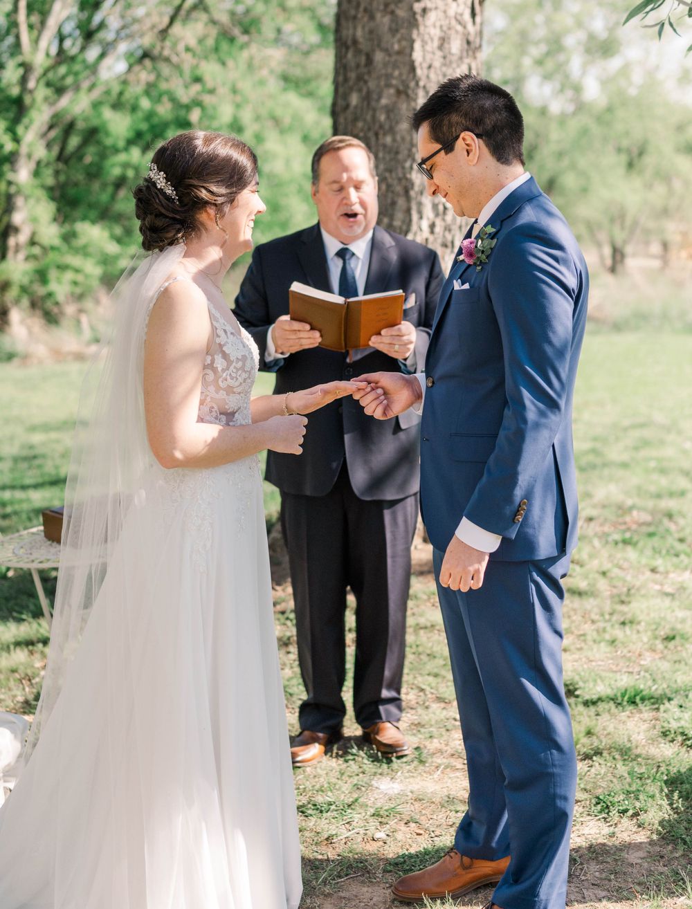 Outdoor wedding ceremony with couple exchanging vows under trees.