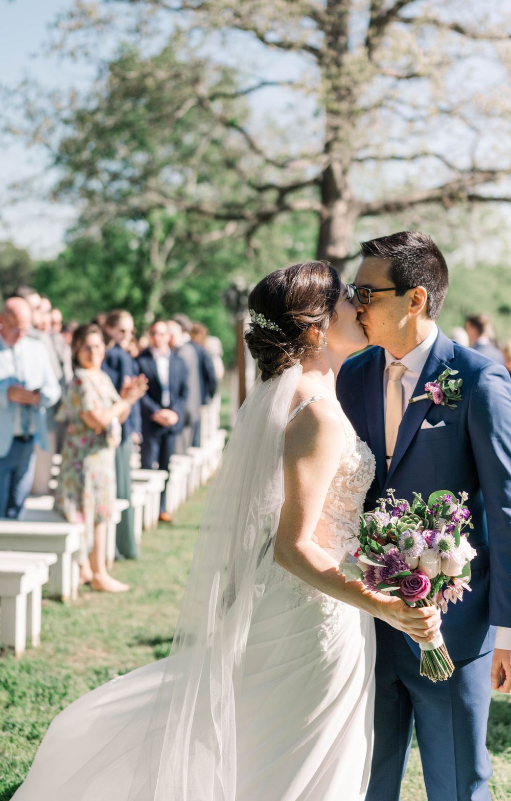 Couple sharing romantic moment at outdoor wedding with natural backdrop.