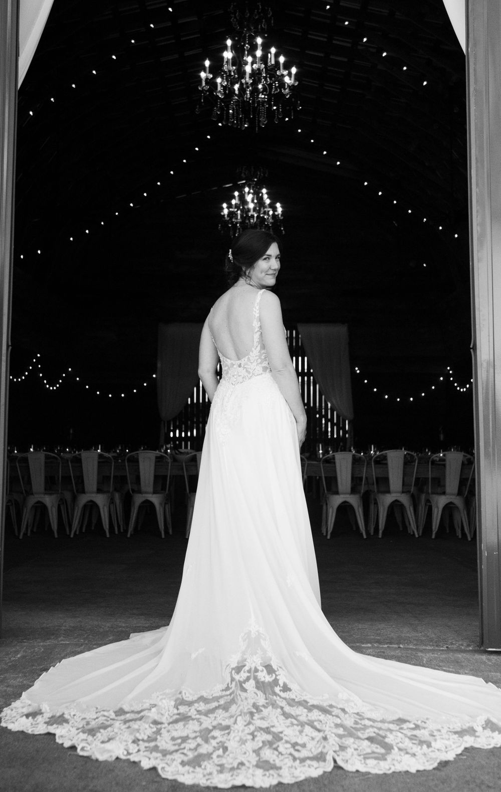Elegant bridal gown with lace detail and long train under crystal chandeliers.