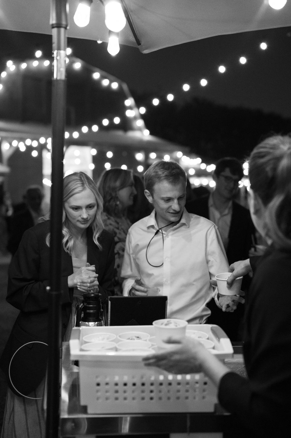 Guests mingle under string lights at an evening outdoor reception.