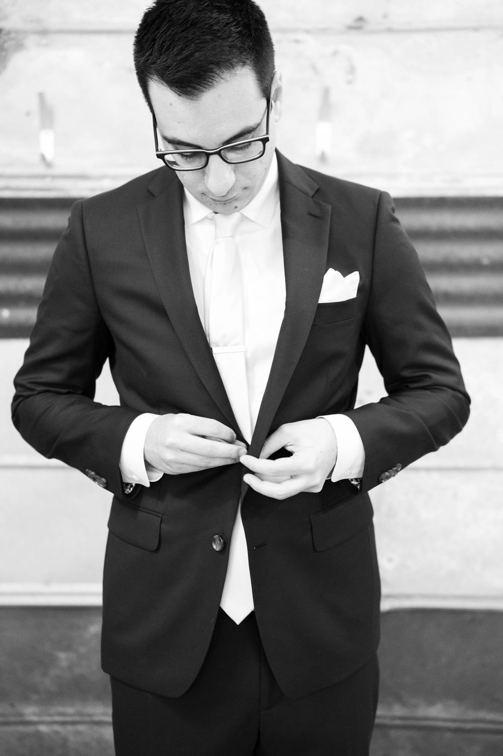 Black and white photo of a person in formal attire adjusting their tie.