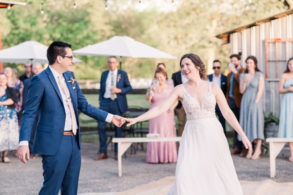 Couple dancing at outdoor reception with guests watching in background.