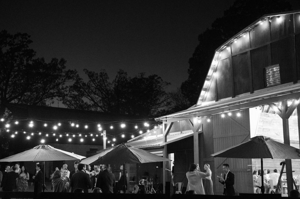 Black and white nighttime view of an outdoor wedding venue with string lights and barn architecture. The 1932 Barn Venue, Charlotte, NC