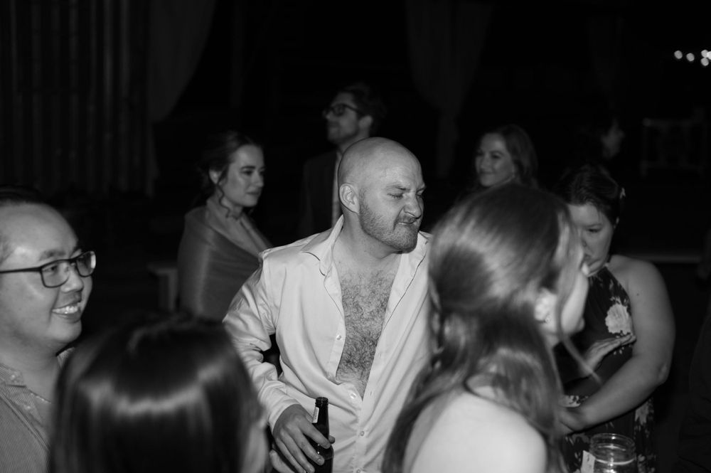 Black and white photo of guests dancing and mingling at an evening reception.