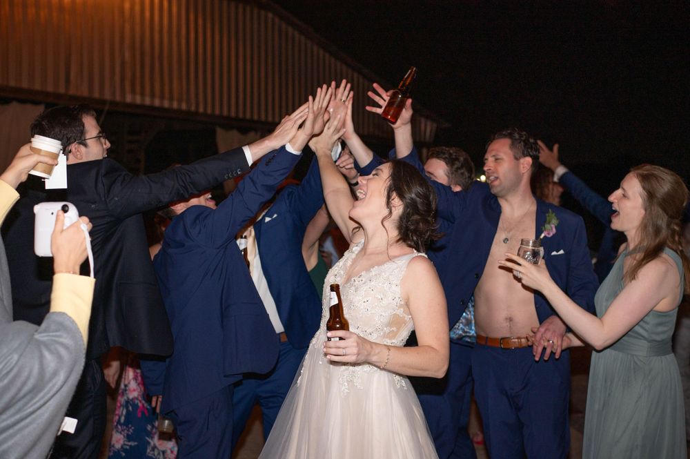 Wedding party celebrates with raised hands during a lively reception dance.