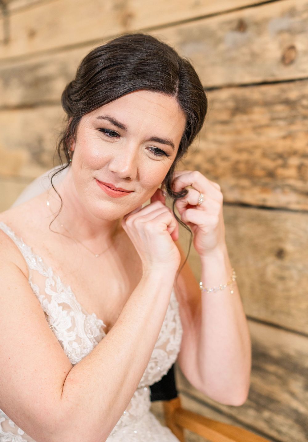 Beautiful bridal portrait with lace dress against rustic wooden wall backdrop.
