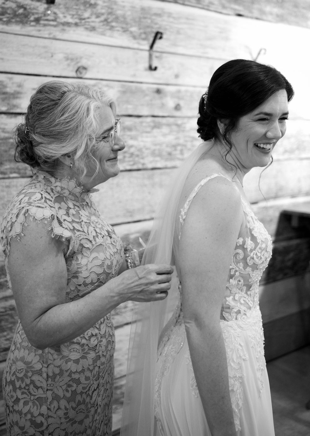 Sweet candid moment of getting ready with lace-clad attendant helping with wedding dress.