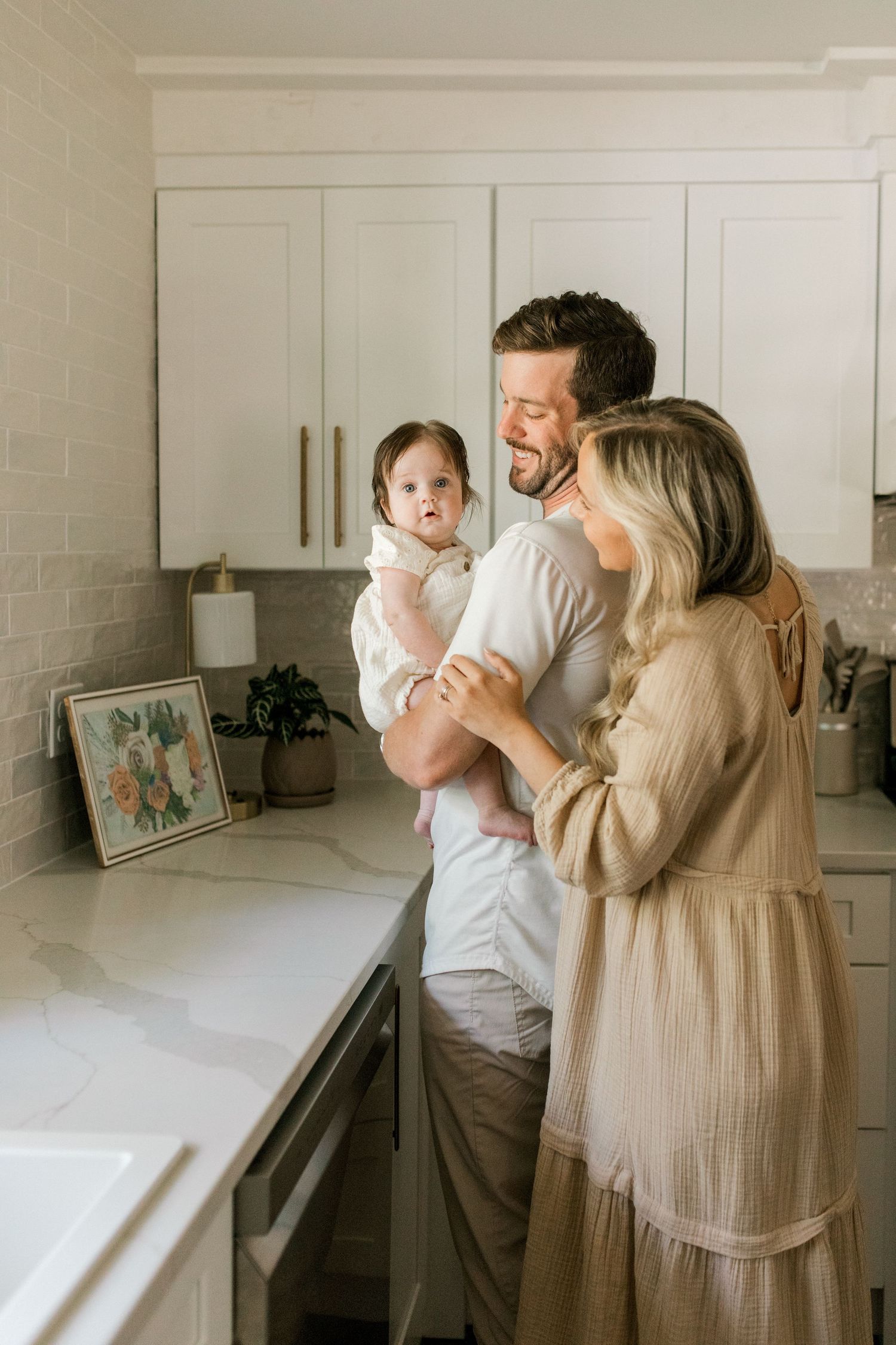 Happy family gathering in their sleek white kitchen sharing joyful expressions.