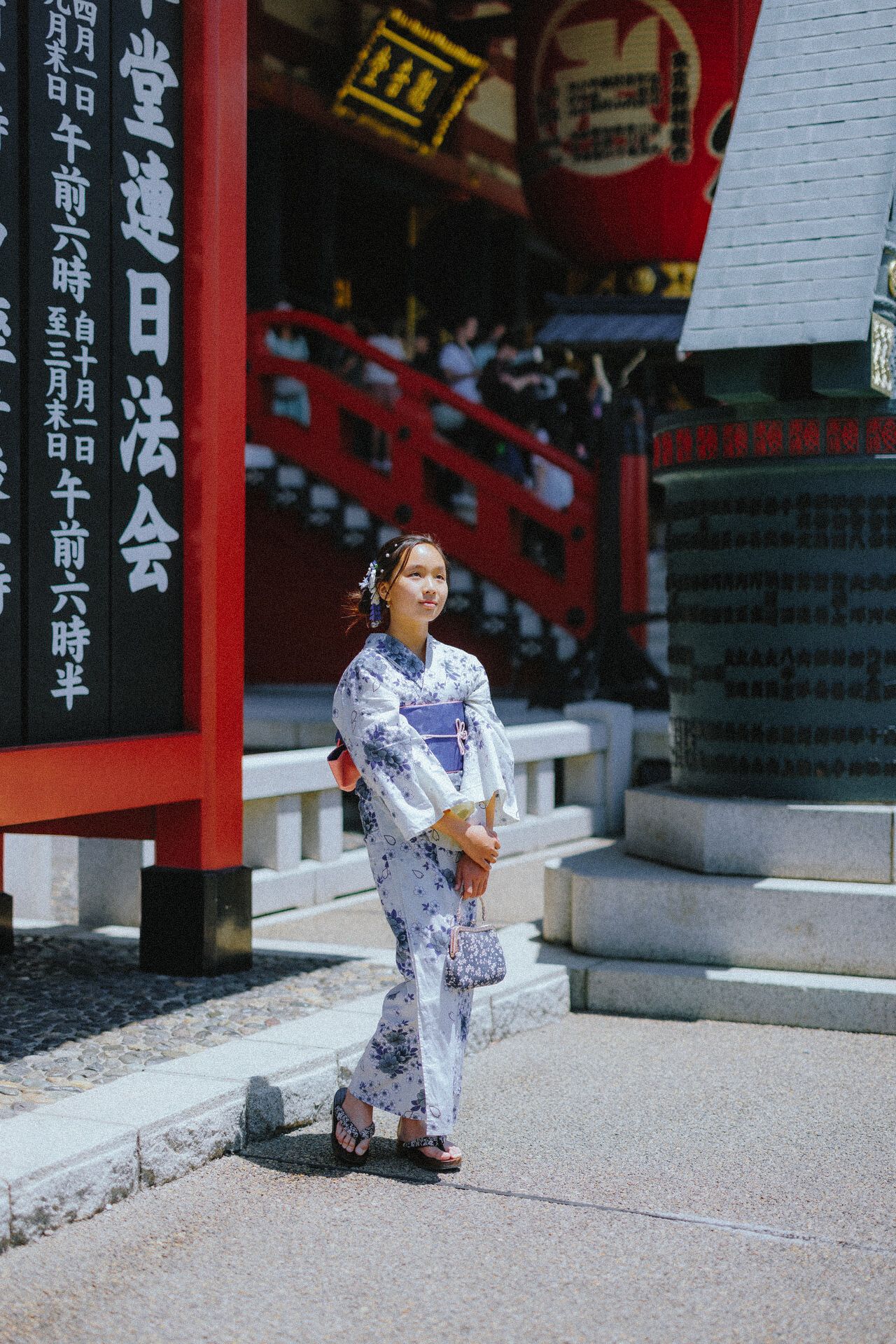 Person wearing blue and white yukata walking along traditional Japanese temple path with red gates.