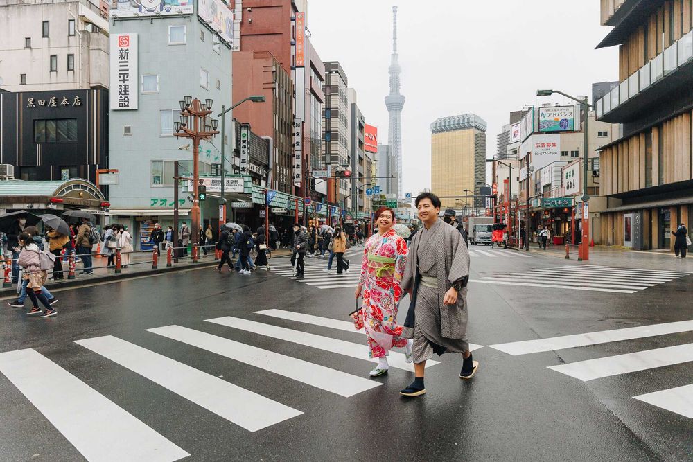 Couple in traditional Japanese clothing crossing a street with Tokyo Skytree visible.
