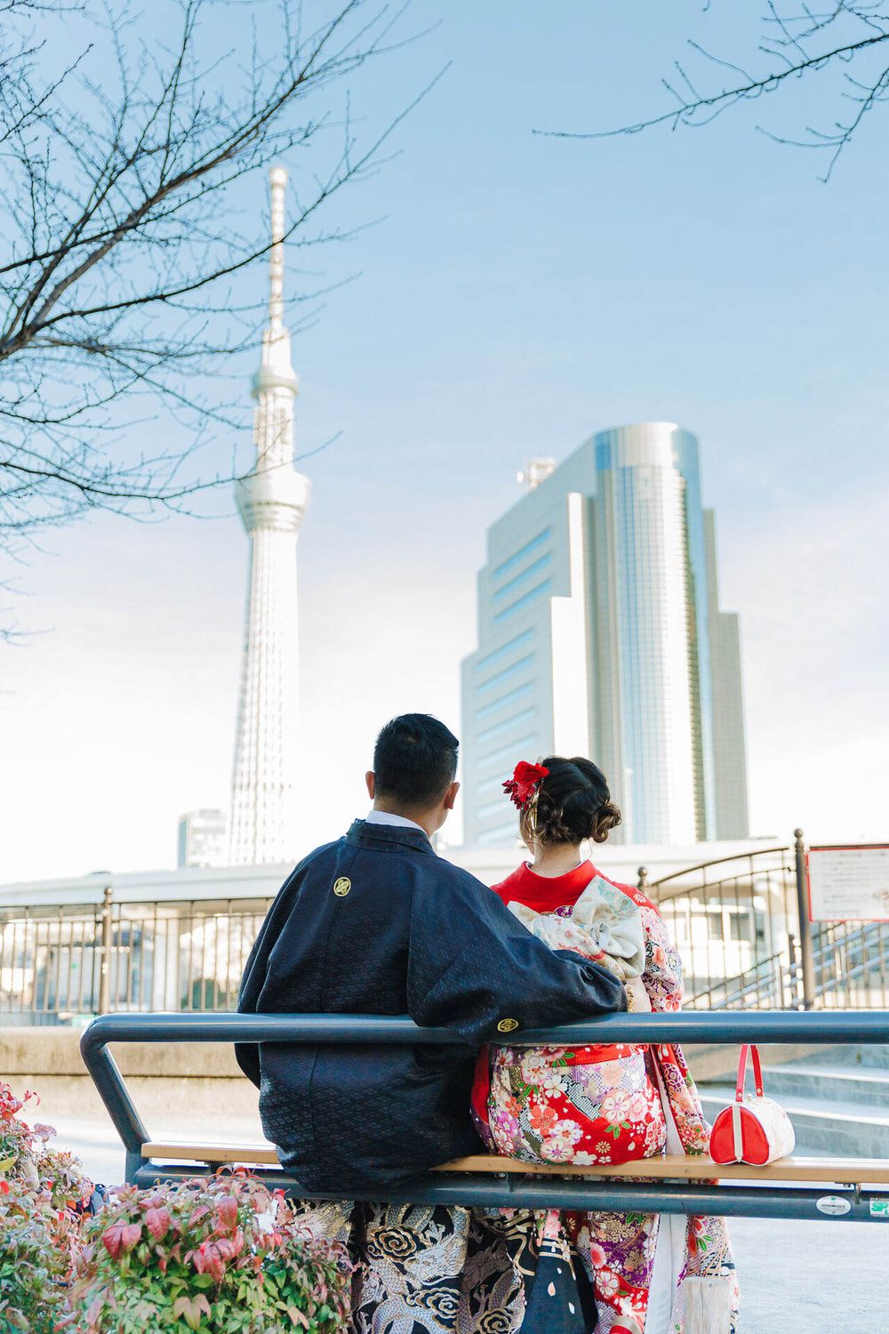 Couple in traditional Japanese dress viewing Tokyo Skytree from bench.