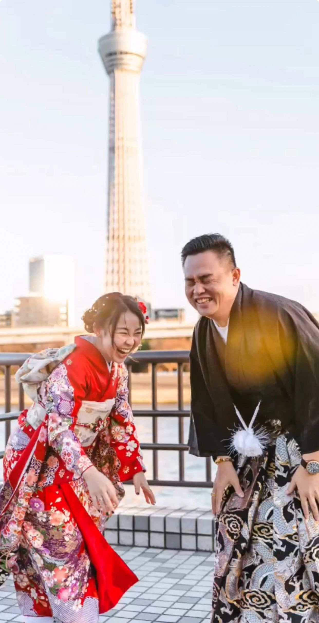 Two people in traditional Japanese dress sharing a joyful moment near Tokyo Skytree.