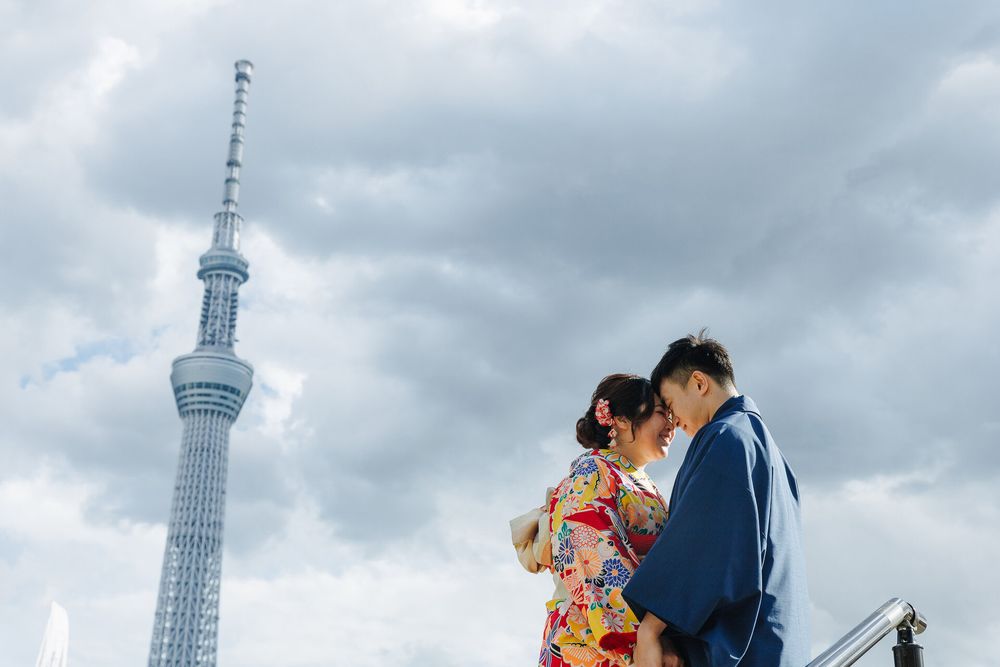 Intimate moment between couple in traditional Japanese clothing with Tokyo Skytree in background.