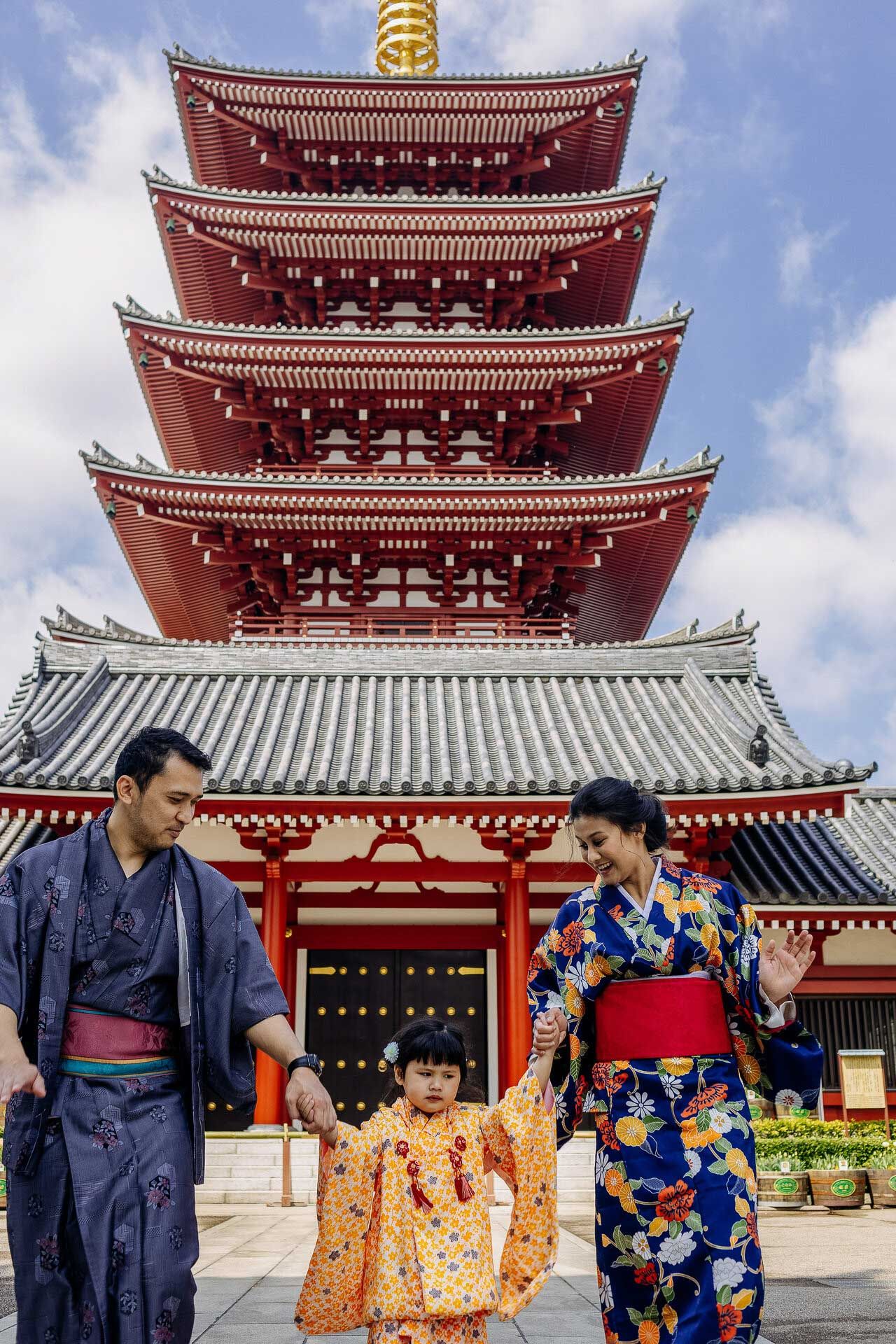 Family in colorful yukatas standing in front of a five-tiered red pagoda at Sensoji Temple in Tokyo.