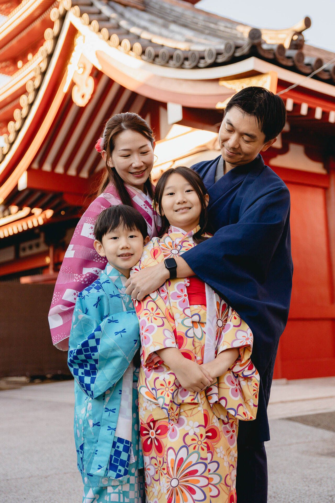 A family group wearing colorful yukatas poses together against red temple architecture.