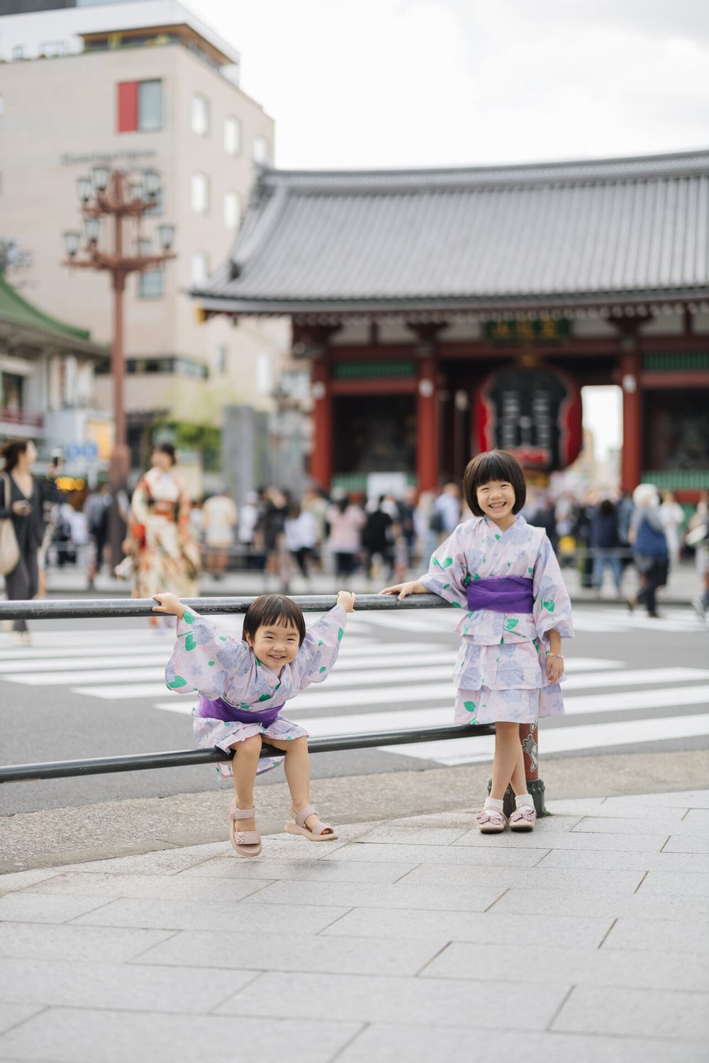 People in yukata posing playfully at crosswalk near Sensoji Temple in Tokyo.
