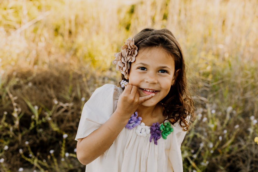 Sweel girl Shasha portrait, holding a small flower and shyly smiling.