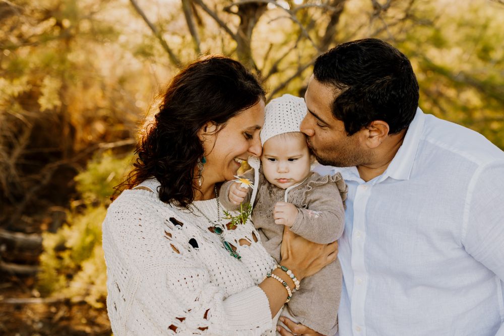 Joelle and David standing and holding their baby Liv between them.