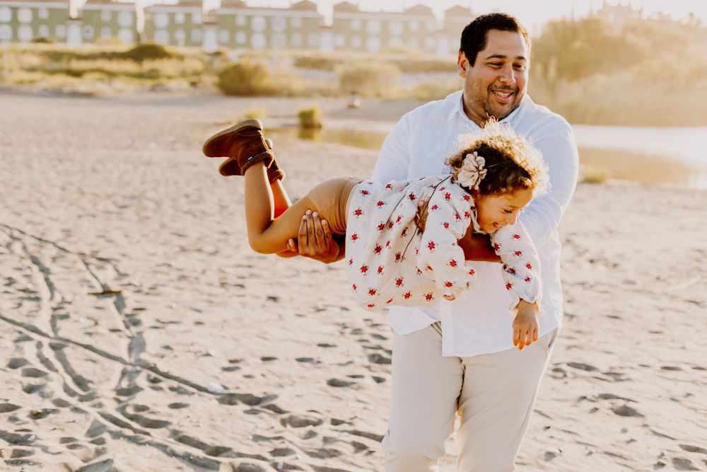 Father holding  Romi in his hands when she is horizontal, looking at the ground, and flying like airplane.