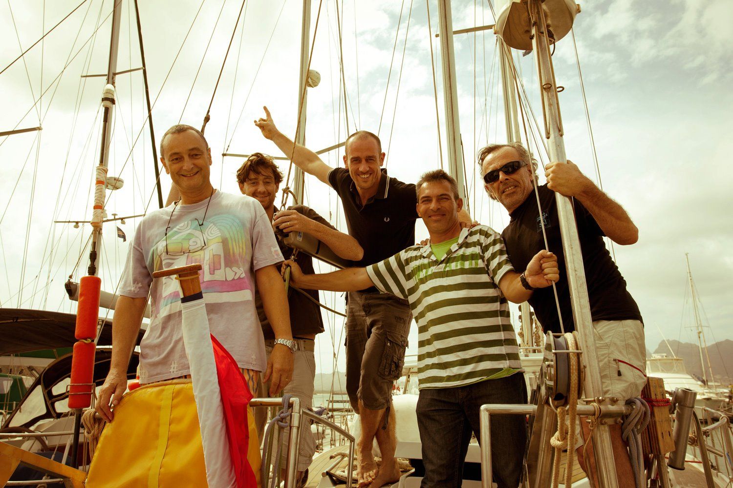 Group standing together on the deck of a sailboat with nautical equipment visible.