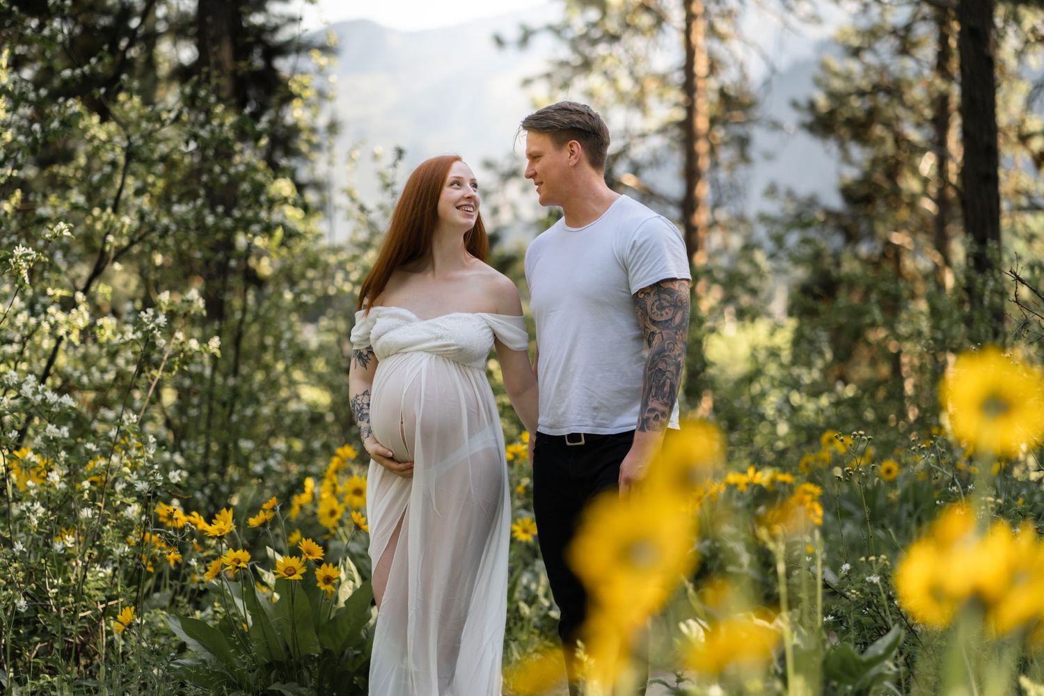 An intimate maternity photoshoot amidst blooming yellow wildflowers in the mountains.