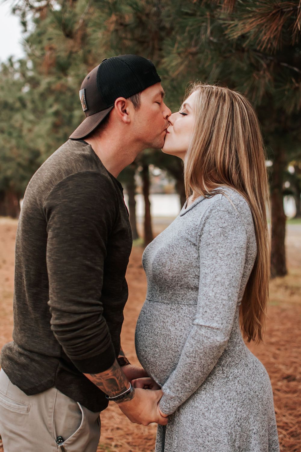 Intimate moment between expecting couple during maternity photoshoot in wooded setting in Pasco, Washington park.