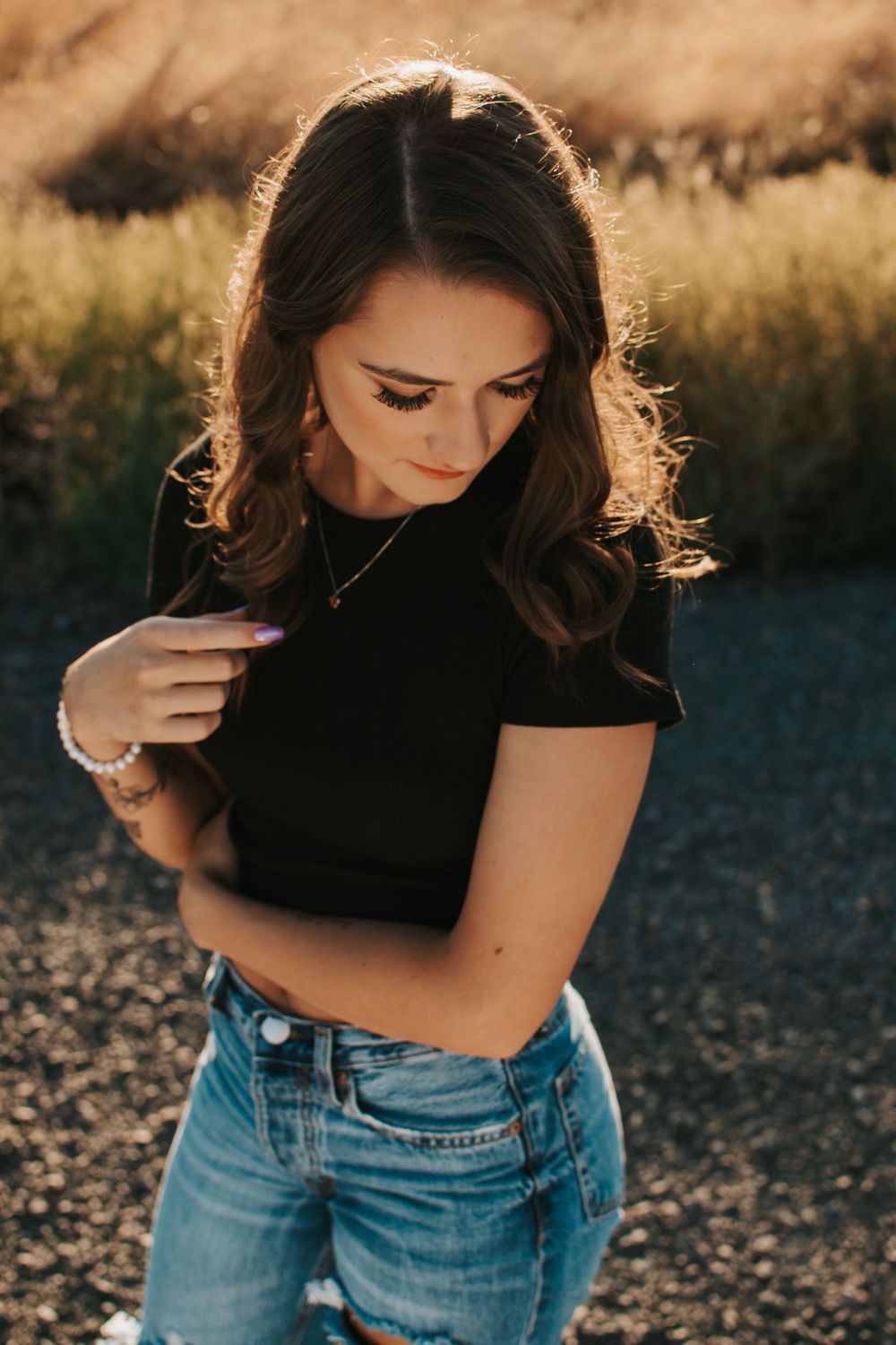 High school senior in black top and jeans photographed in golden sunlight in Tri Cities, Washington.