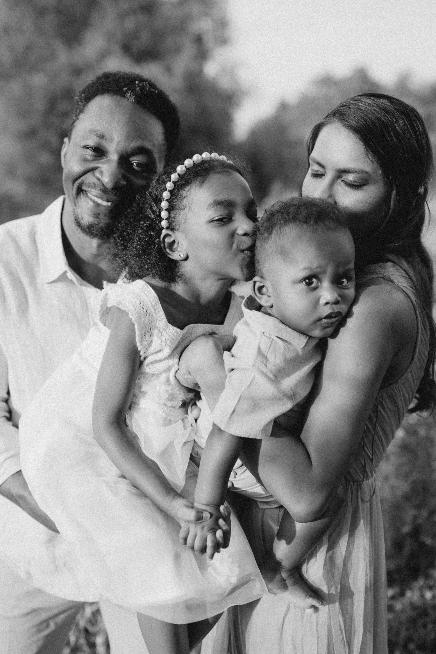 a mum and dad kissing and holding their two kids in their arms