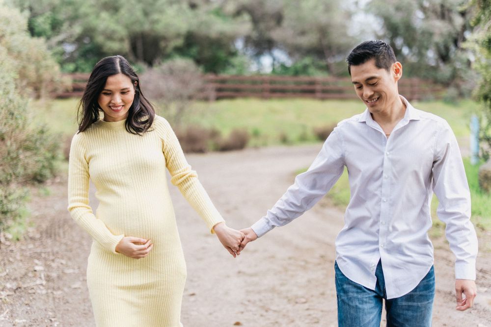 Couple walking hand in hand on a dirt path surrounded by nature.