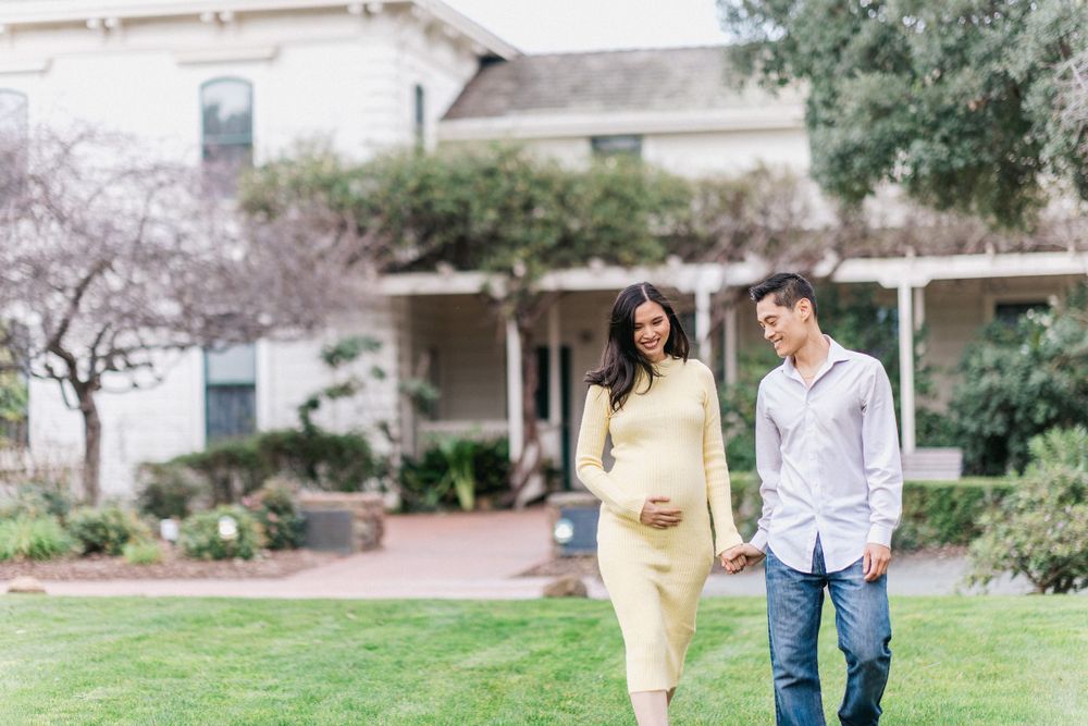 Couple walking together on lawn in front of white historic building.