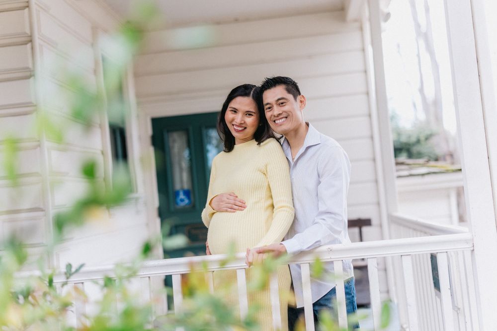 Couple standing together on white porch with green door.