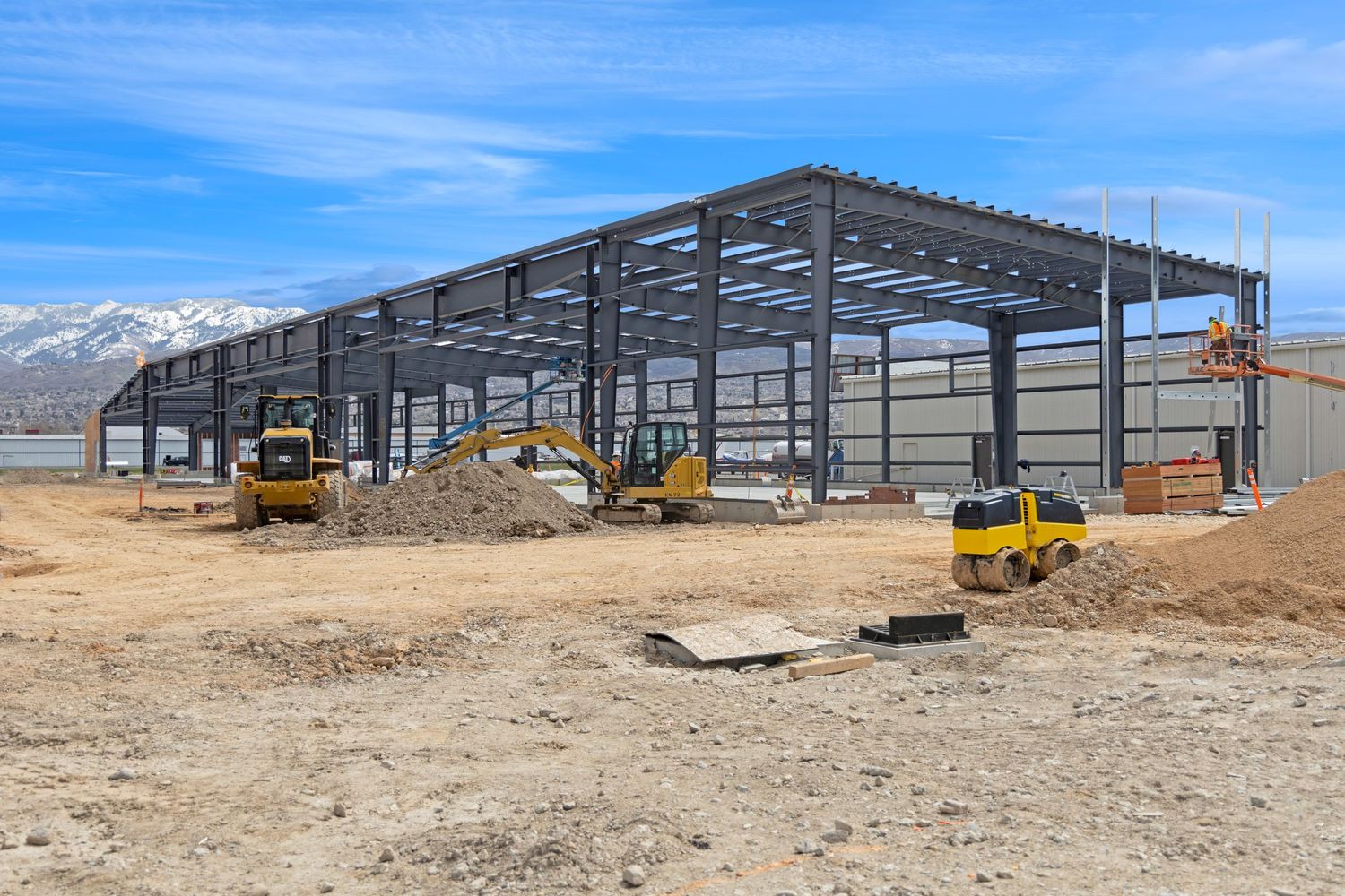 Steel frame commercial building under construction with mountains in background.
