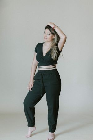 Woman in black two-piece outfit poses against light background.