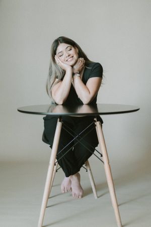 Casual portrait of woman resting head on hands at modern table.