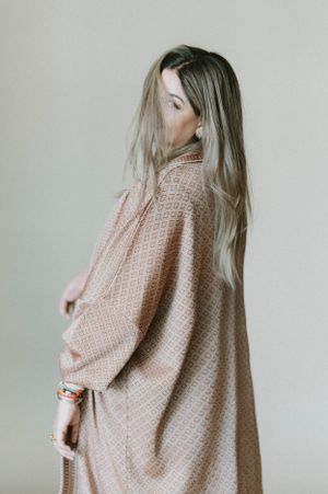 Back view of oversized beige knit cardigan showcased against simple studio background.
