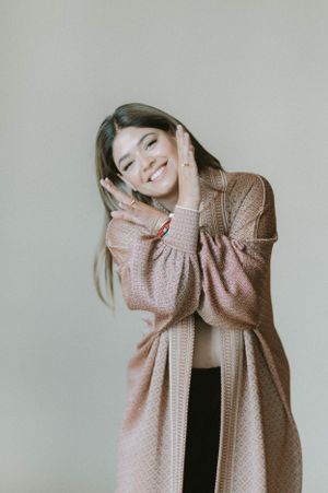 Candid lifestyle portrait showing happiness while wearing cozy pink cardigan in studio.