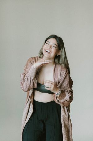 Expressive studio portrait showcasing casual style with pink cardigan and black athletic wear.