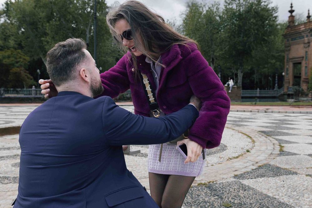 Emotional marriage proposal scene at historic Plaza de España.