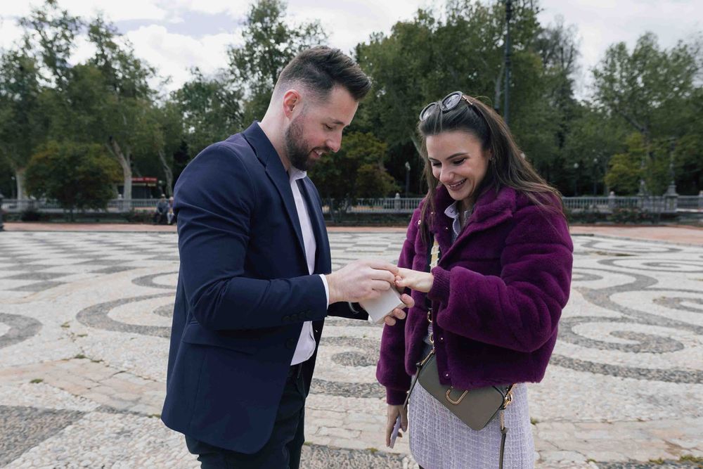 Newly engaged couple examining ring at Plaza de España in Seville.
