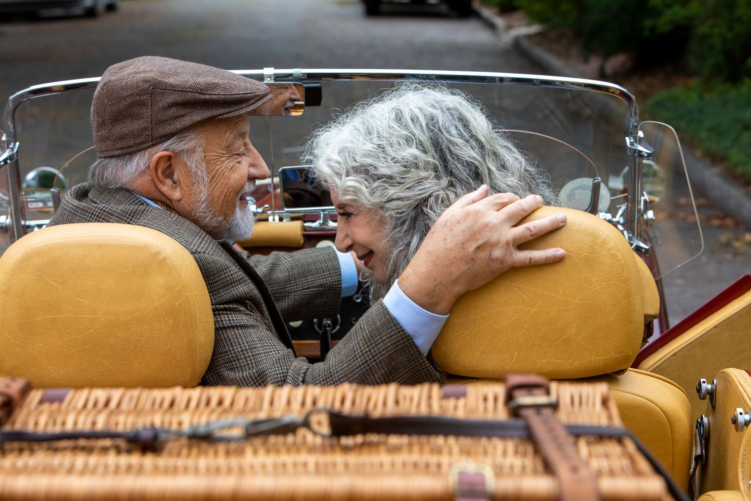 man and woman in antique sports car about to kiss