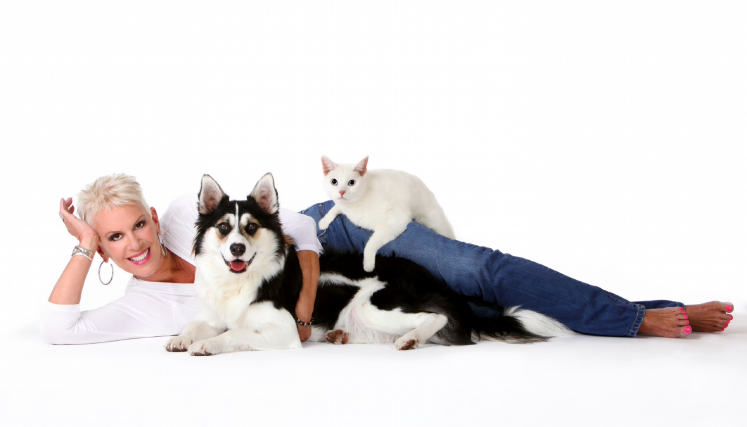 woman laying on white background with a dog and a cat