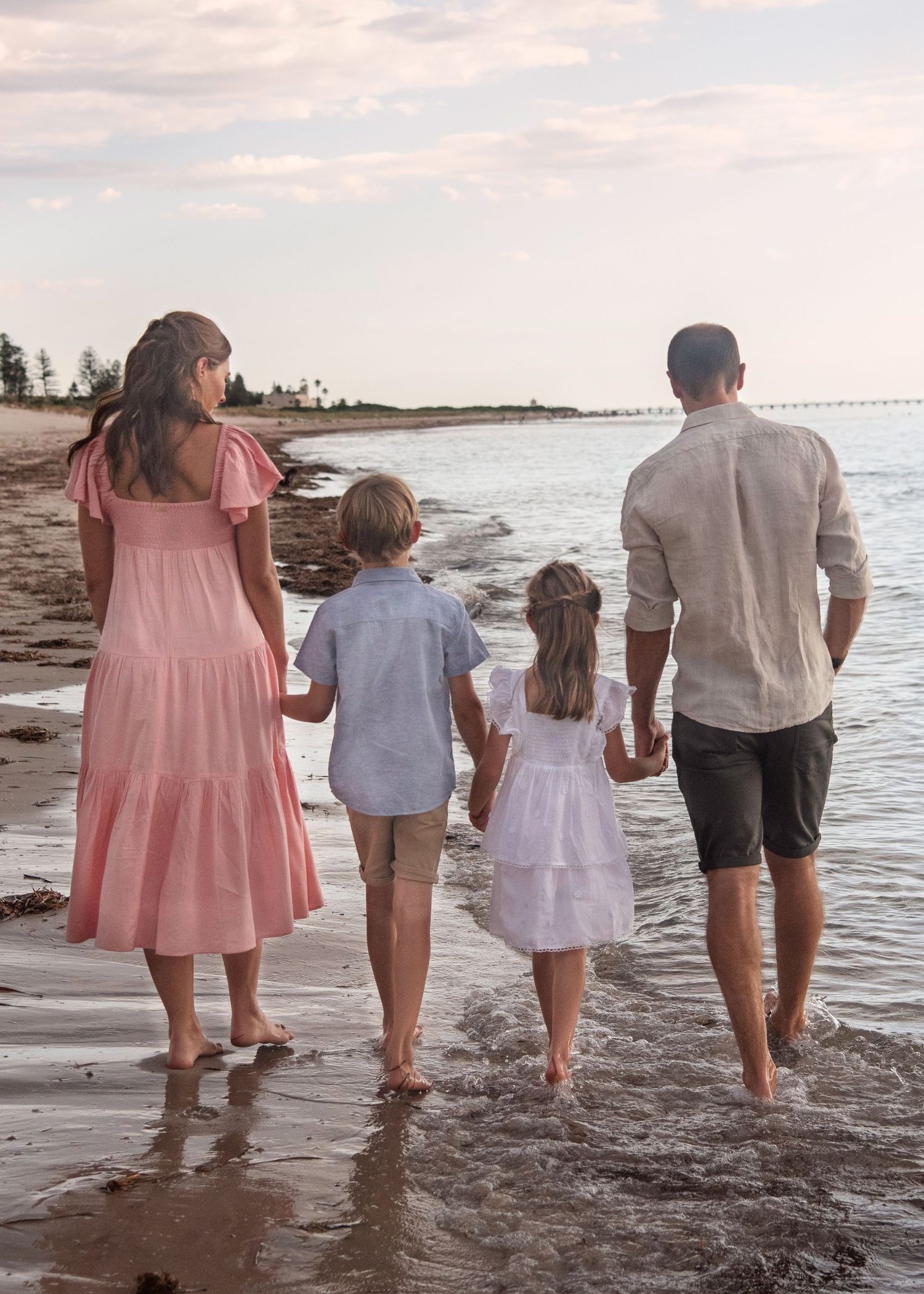 Family beach walk: Woman in pink, girl in white, boy in blue, man in grey. Little Cuddles Photography, Adelaide.