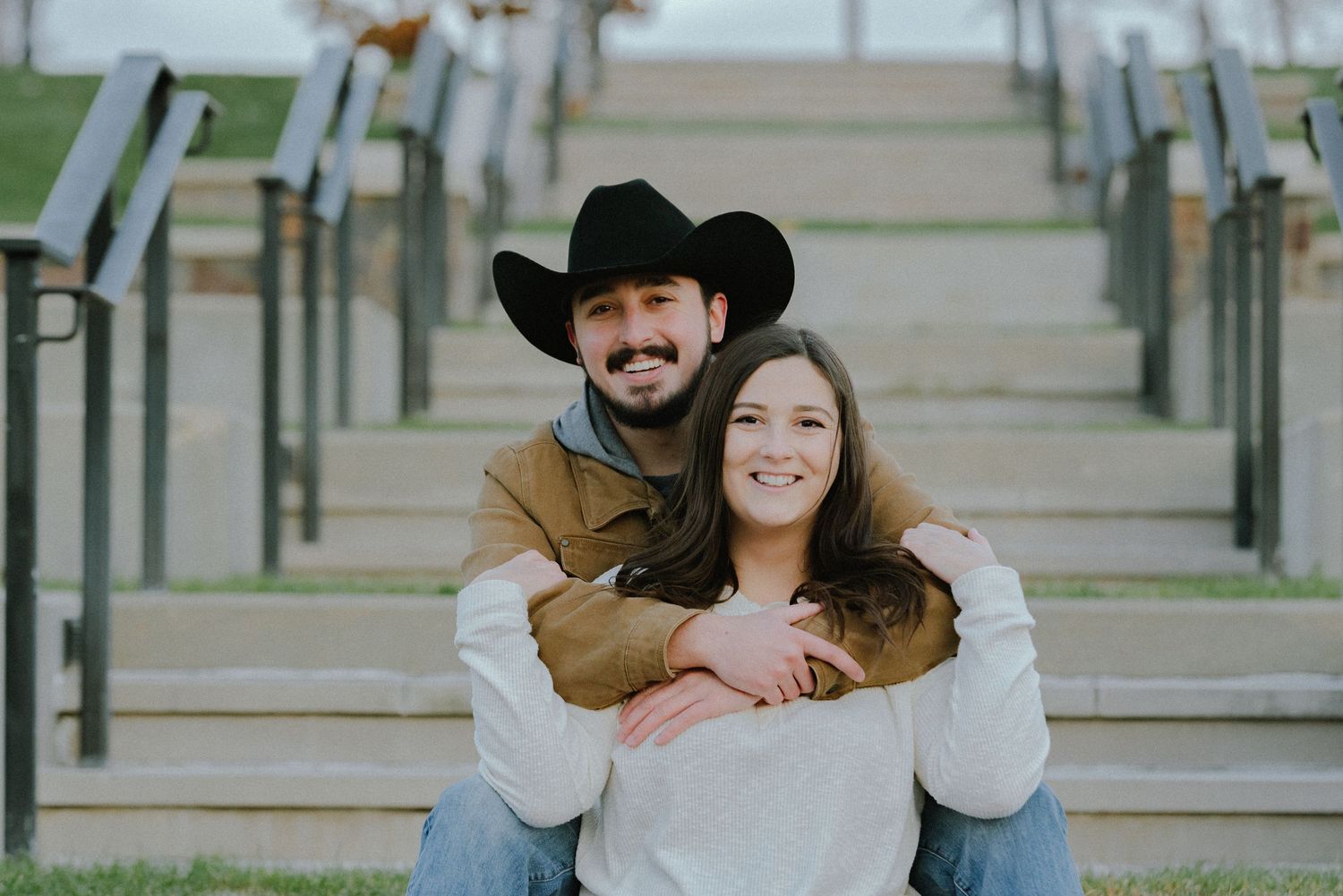 Stylish couple posing on stone steps during an outdoor photoshoot.