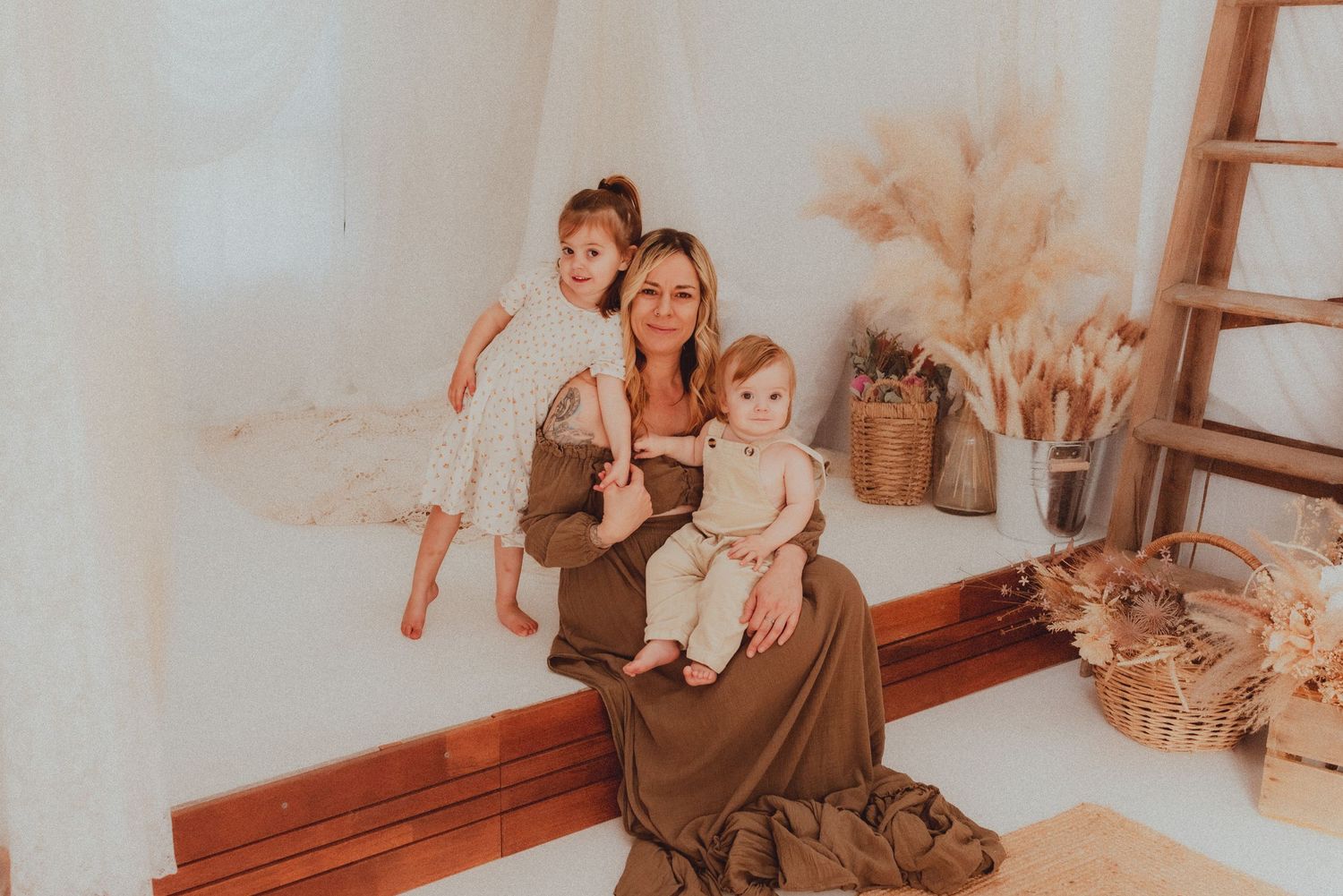Warm-toned indoor family portrait with rustic decor and dried pampas grass.