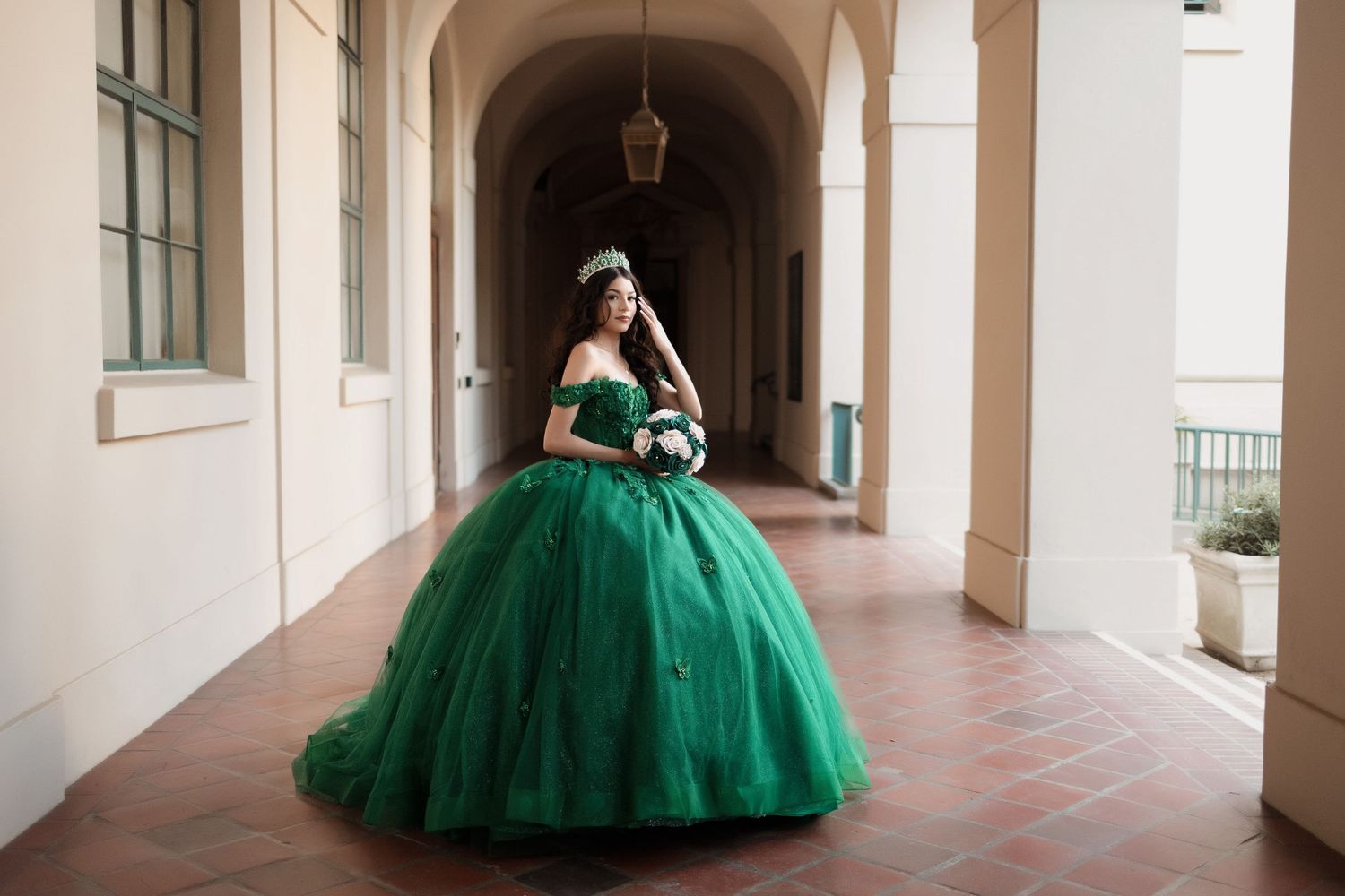 An elegant emerald green ball gown photographed in a Spanish colonial archway.