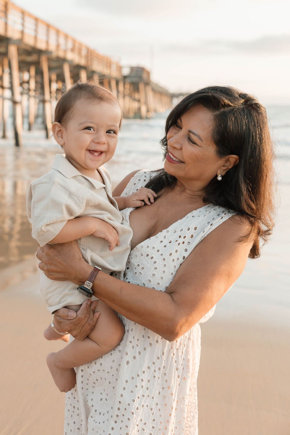 Sweet candid moments captured between family members on a beach during golden hour.